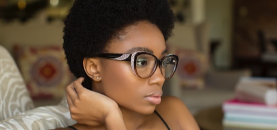Black woman with short hair and glasses gazing to the right