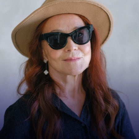 mature woman wearing sunglasses and a wide brim hat smiling