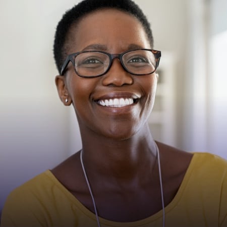 younger black woman with short hair wearing a yellow shirt and glasses, looking straight at the camera and smiling