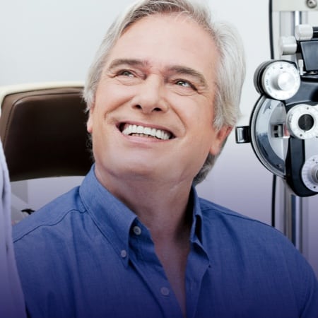 an older white male sitting during an eye exam looking up and to the side